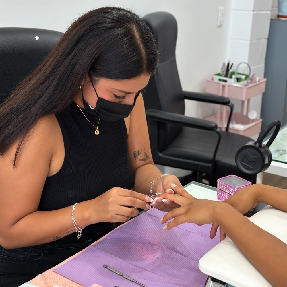Nail artist performing a manicure at Nail Queen